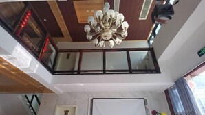 A hotel lobby with a chandelier, a large window, and a door. - Fengle Yiyuan Inn (Xiangshan)