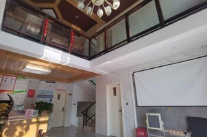 Un vestíbulo de hotel con una recepción, una escalera y un amplio ventanal.
