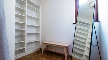 Une pièce avec un banc en bois, un miroir et des étagères blanches.