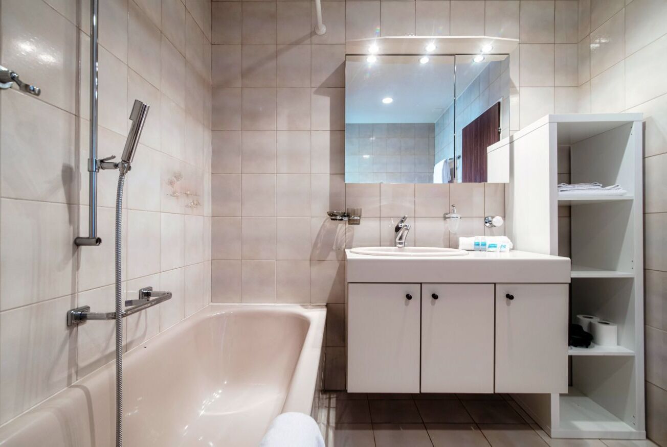 Ein modernes Badezimmer mit einer Badewanne, einem Waschbecken mit Spiegel und einer Duschbrause.