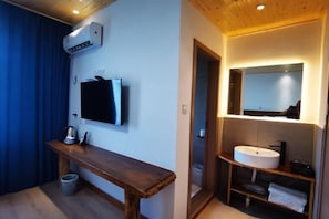 Un baño moderno con tocador de madera, un espejo grande y lavamanos integrado.
