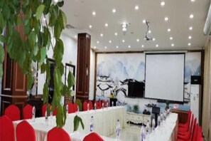 A conference room with tables, chairs, a projector screen, and a large plant. - Shanxian Matou Inn (Hangzhou)