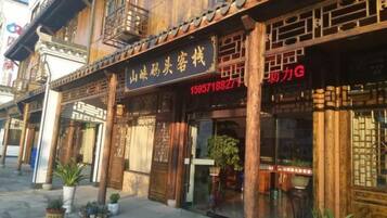A traditional wooden building with a signboard, potted plants, and a visible entrance.