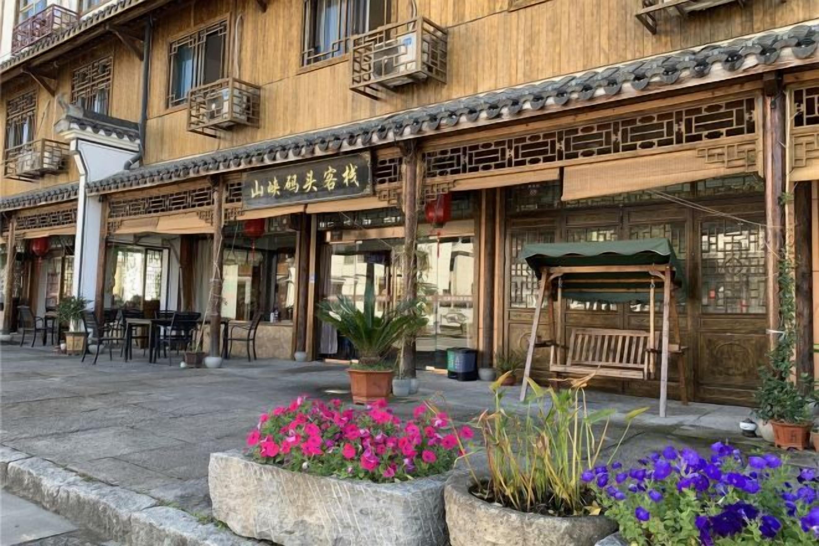 A traditional wooden building with a sign, outdoor seating, and potted plants.