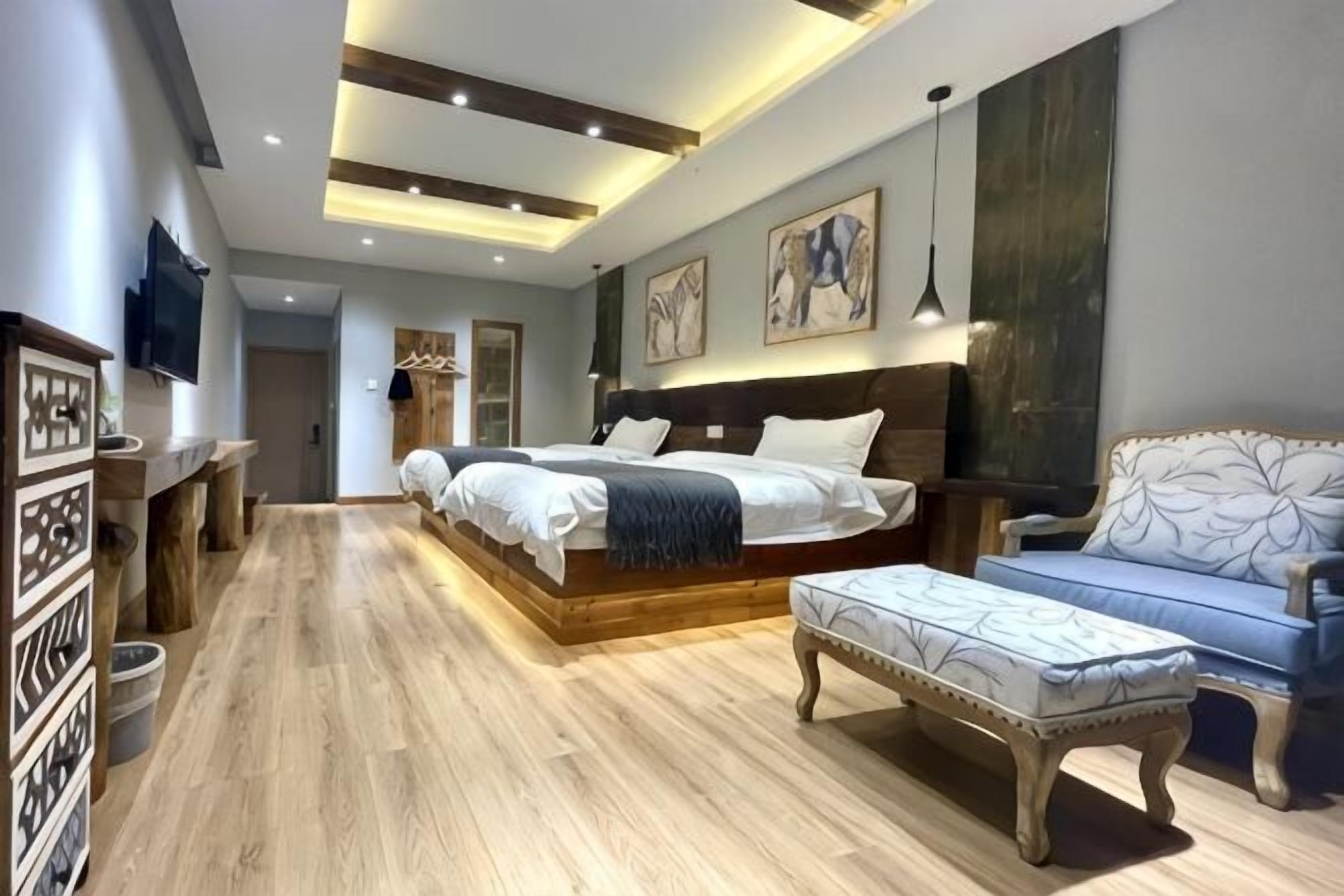 Ein Schlafzimmer mit einem großen Bett, Nachttischen, einem Sofa, Holzboden und einem an der Wand befestigten Fernseher.