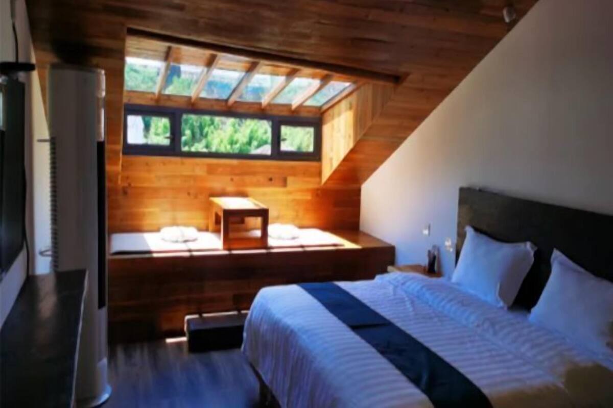 Ein Schlafzimmer mit Oberlicht, einem Bett, einem Nachttisch und einer kleinen Holzbank.