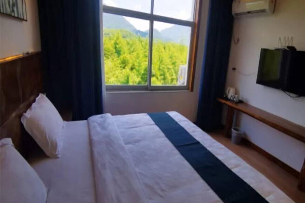 Ein Hotelzimmer mit Bett, Fenster mit Bergblick, Fernseher und Ablagefläche.