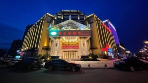 A hotel with a grand entrance, a signboard with Chinese characters, and a modern facade.