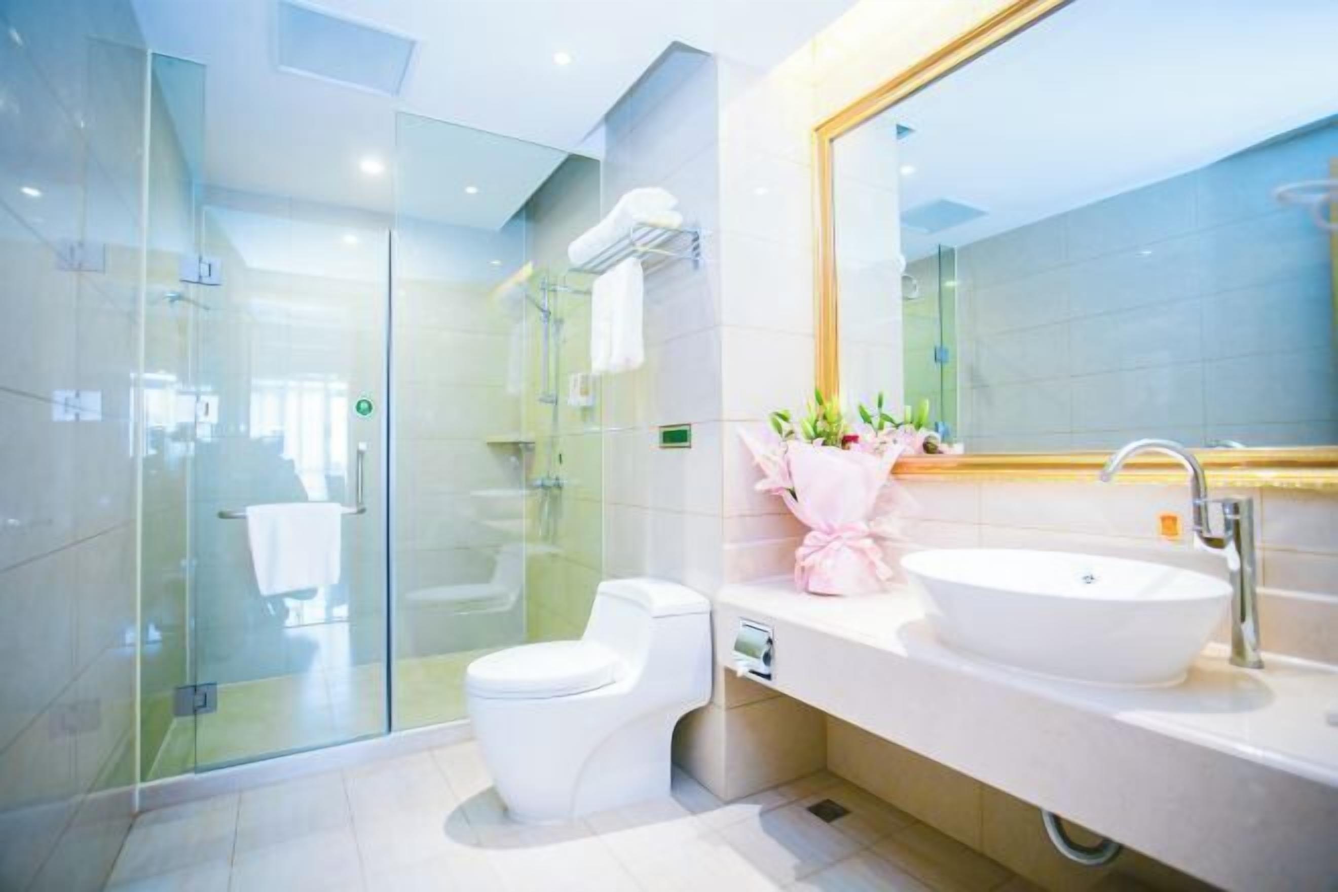 A modern bathroom with a glass-enclosed shower, a white toilet, and a large sink with a mirror above it.