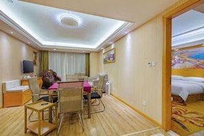 A hotel room with a dining area, a massage chair, a TV, and a bed. - Vienna Hotel (Anqing Guangcai Qijie) (Anqing)