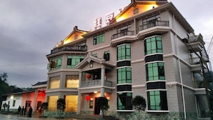 A multi-story hotel with traditional architectural elements, including a balcony on the second floor and a staircase on the right side. - Hongdou Mountain Villa (Pingyuan)