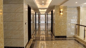 A marble-floored corridor with a glass door, a wall-mounted light fixture, and a patterned floor design. - Hongdou Mountain Villa (Pingyuan)