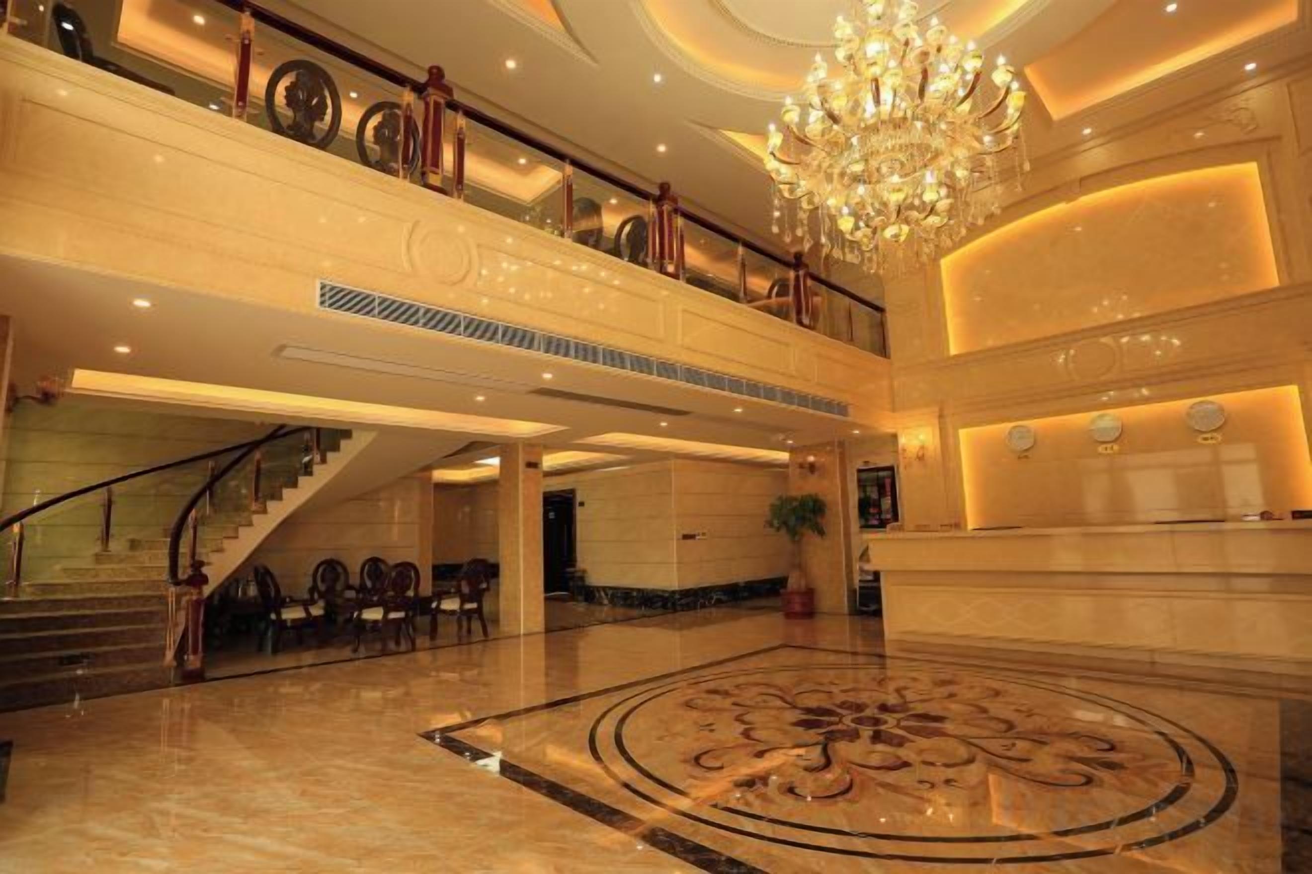 A grand lobby with a marble floor, a staircase, and a chandelier.