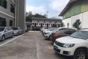 A parking lot with multiple cars parked in front of a building with a green roof and a white facade. - Hongdou Mountain Villa (Pingyuan)
