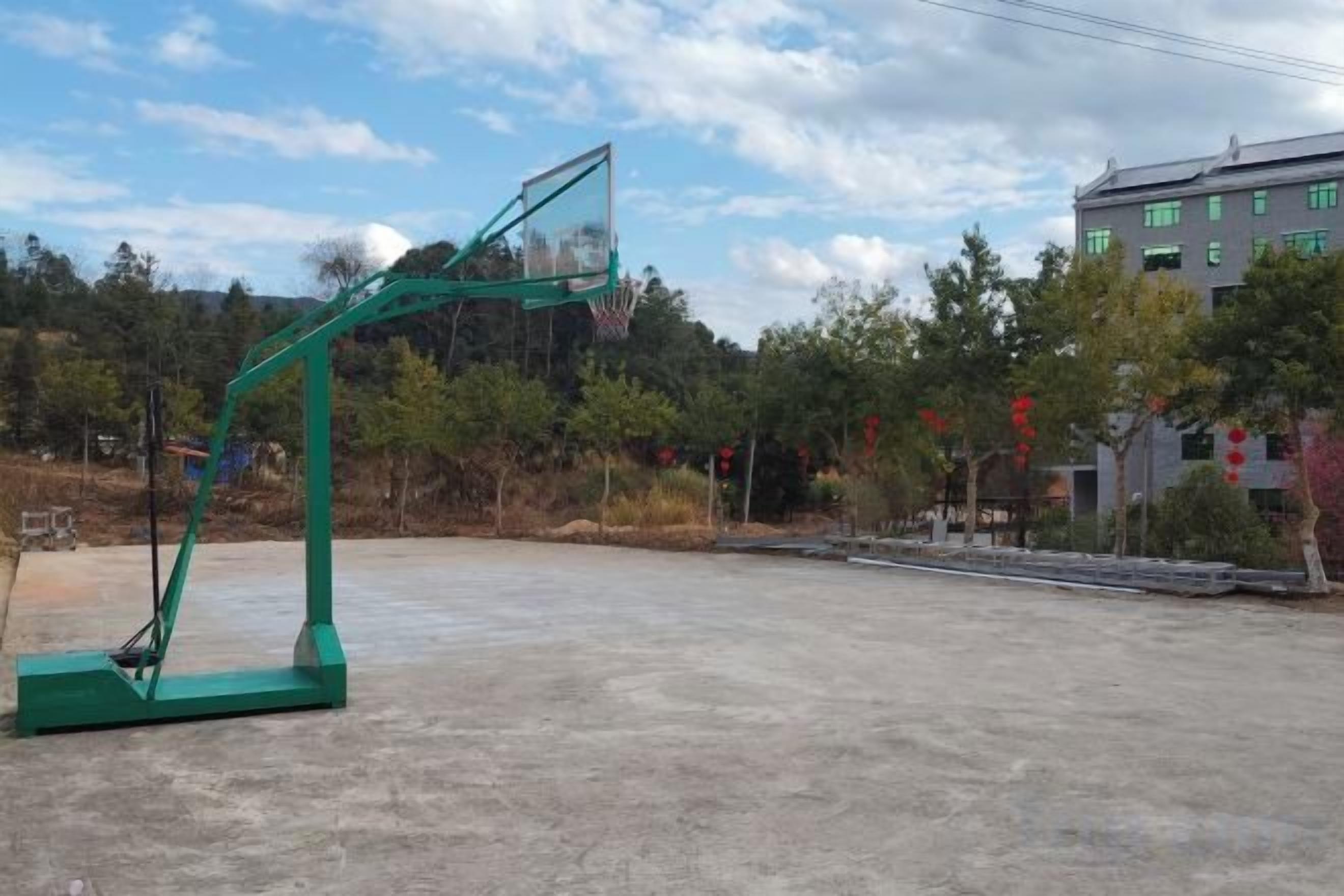Una cancha de baloncesto al aire libre con un aro de baloncesto verde.
