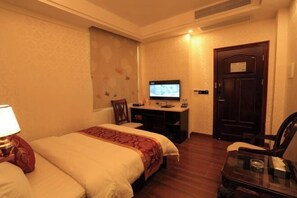 A hotel room with a bed, a desk with a computer, a chair, and a door. - Hongdou Mountain Villa (Pingyuan)