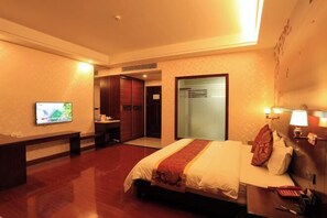 A hotel room with a bed, a desk, a television, and a door leading to a bathroom. - Hongdou Mountain Villa (Pingyuan)