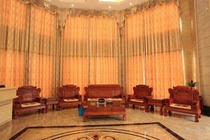 Un hall d’entrée avec un comptoir de réception, quatre canapés en bois et une moquette à motifs.