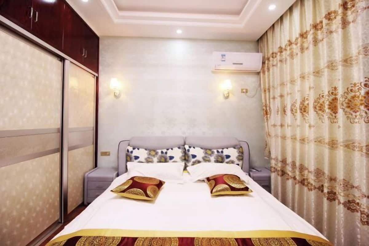 Habitación de hotel con cama, mesitas de noche, equipo de aire acondicionado y apliques decorativos.