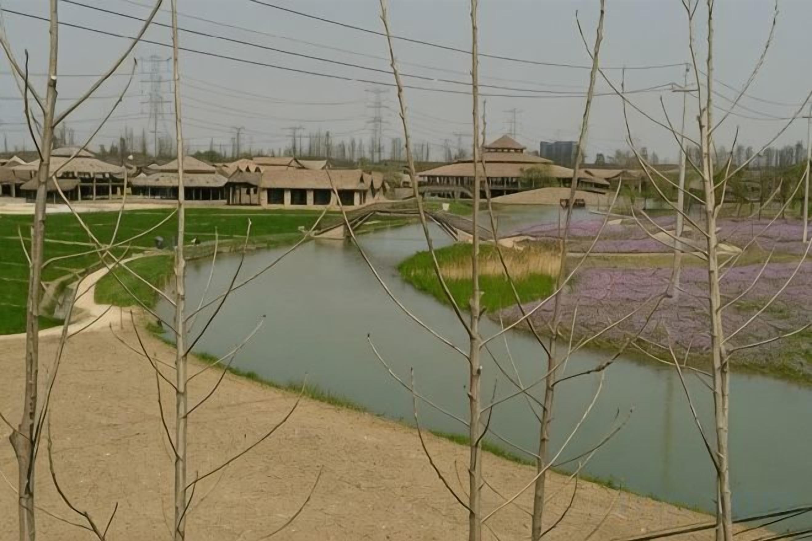 Un río con un puente, rodeado de campos y edificios.