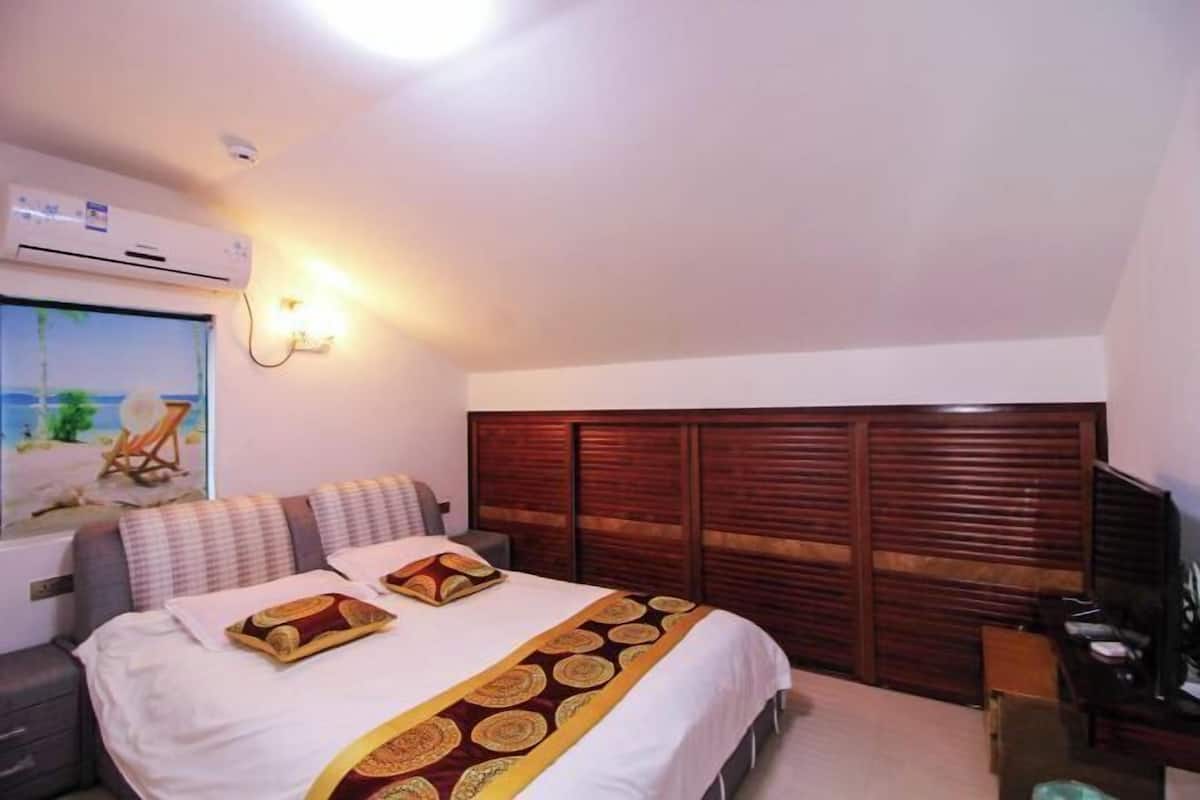 Un dormitorio con cama, mesita de noche, escritorio, lámpara, equipo de aire acondicionado y ventana con vistas.