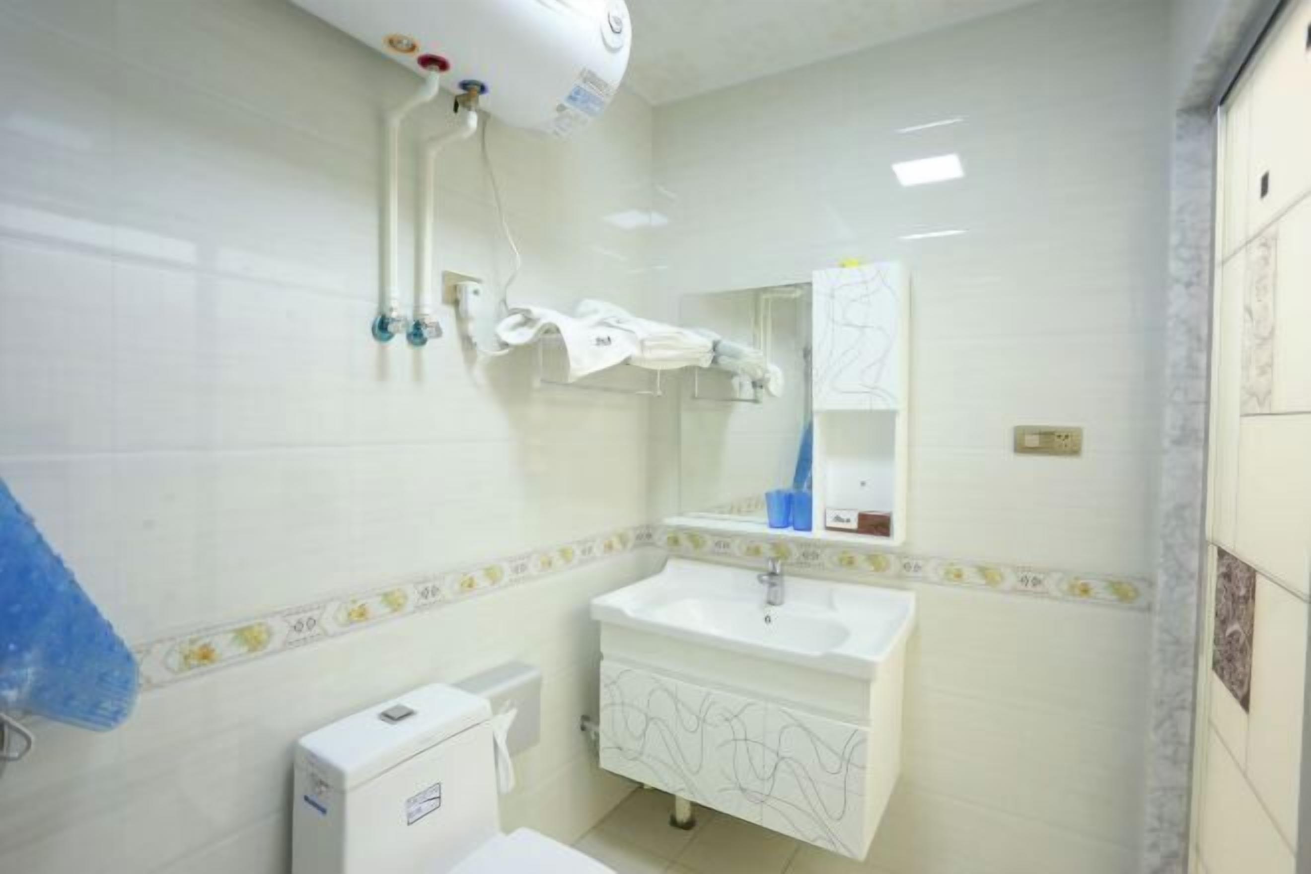 Casa de banho com lavatório branco, espelho e porta-toalhas.
