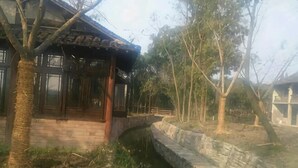 A traditional building with a brick facade, a wooden structure on the left, and a stone wall on the right. - Xingfu Yayuan Guesthouse (Tongxiang)