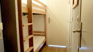 Une chambre avec un lit superposé, une porte et un interrupteur sur le mur.