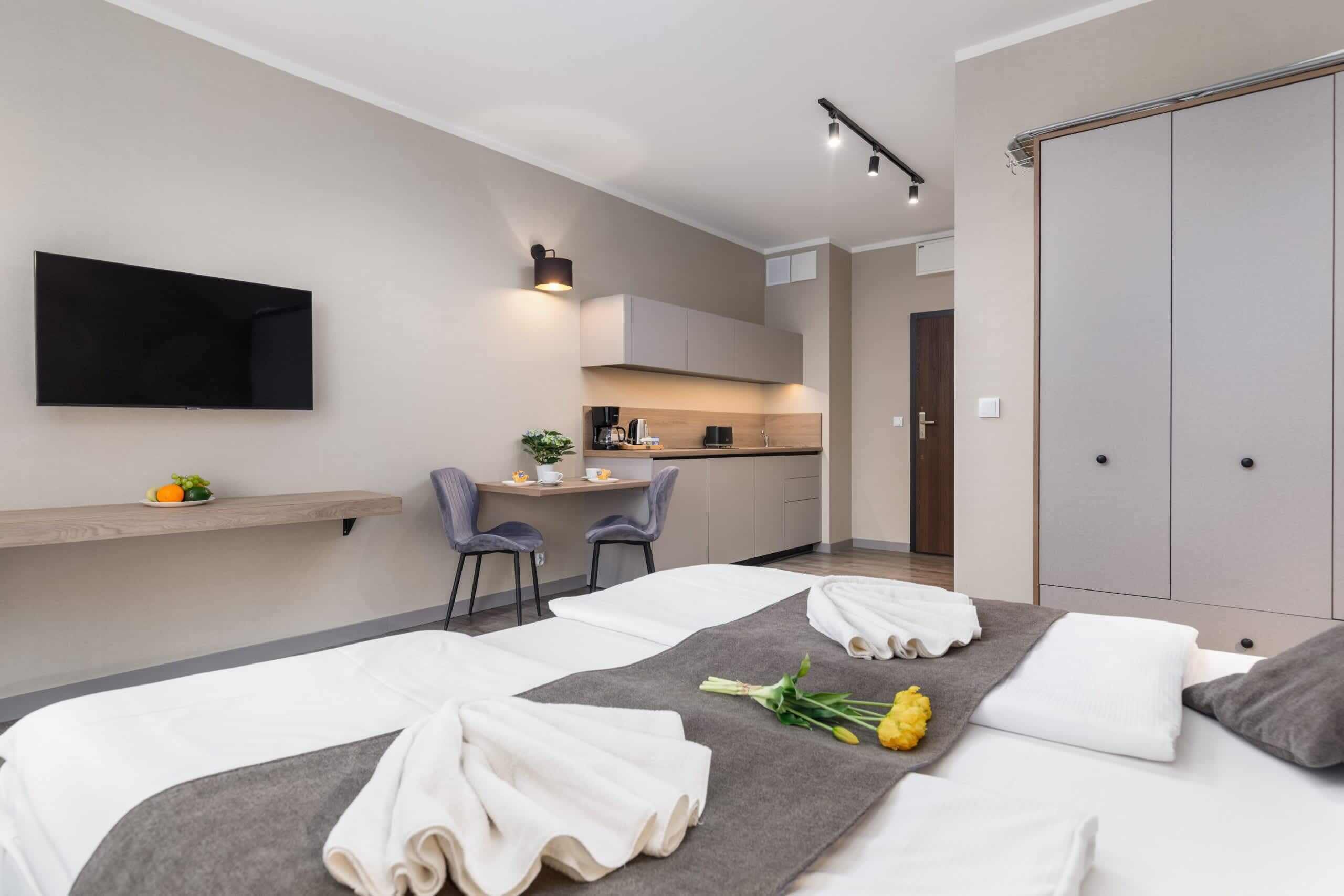 Une chambre d’hôtel moderne équipée d’un lit, d’une petite kitchenette, d’un téléviseur fixé au mur et d’une armoire.