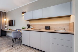 Une cuisine moderne dotée d’un îlot central intégré, d’un téléviseur à écran plat et d’un coin repas avec une chaise.