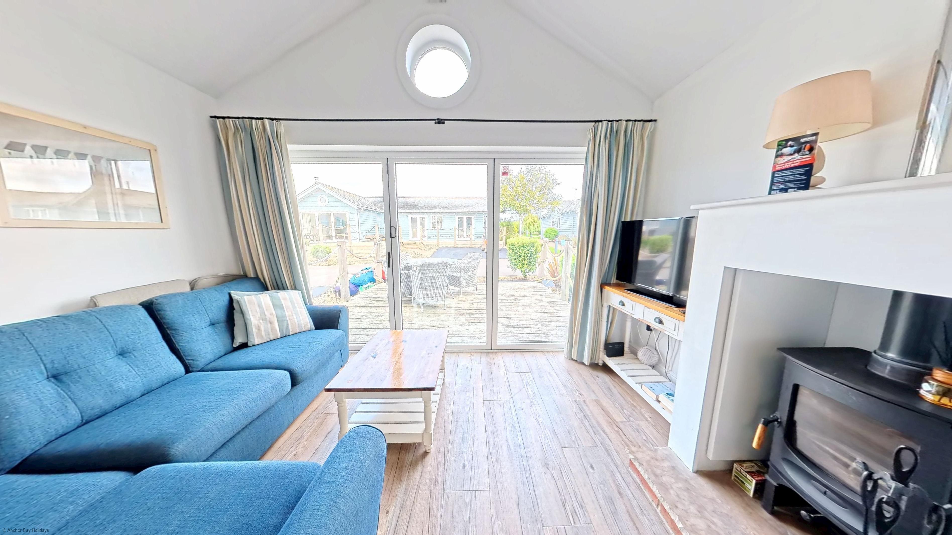 A living room with a sofa, a television, a fireplace, and a view through the glass doors.