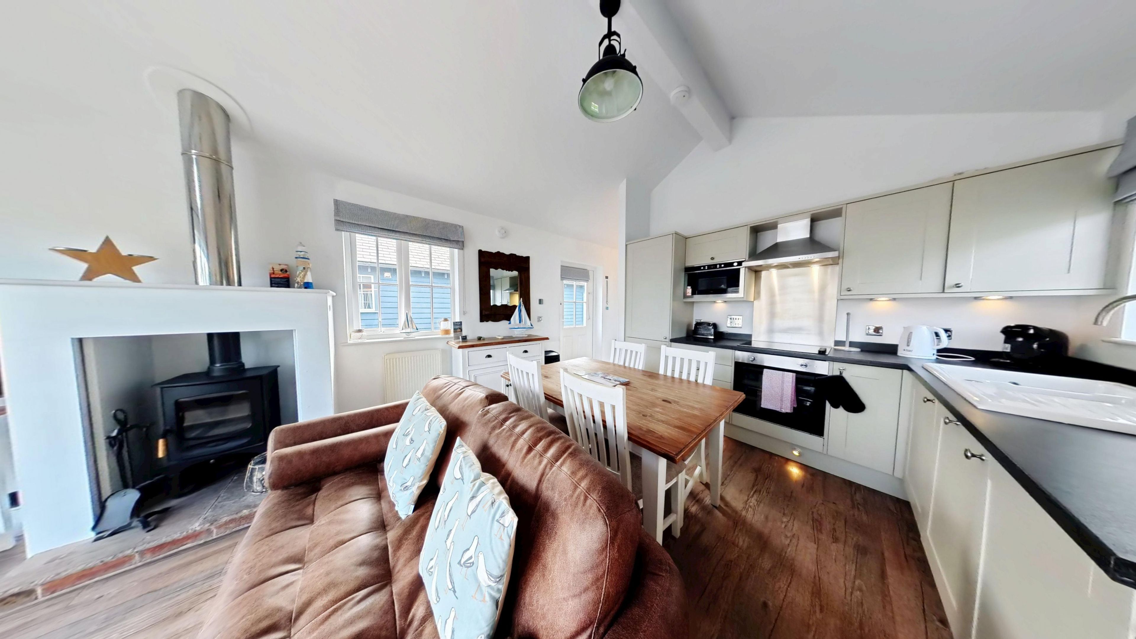 A modern kitchen with white cabinets, a central island, and a built-in oven.