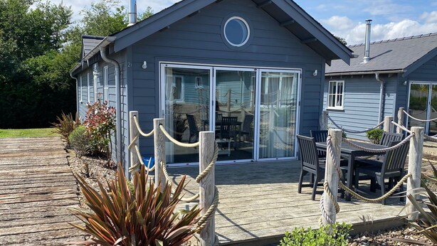Ein Haus mit Terrasse, Essbereich mit Stühlen und Tisch sowie eine große Glasschiebetür.