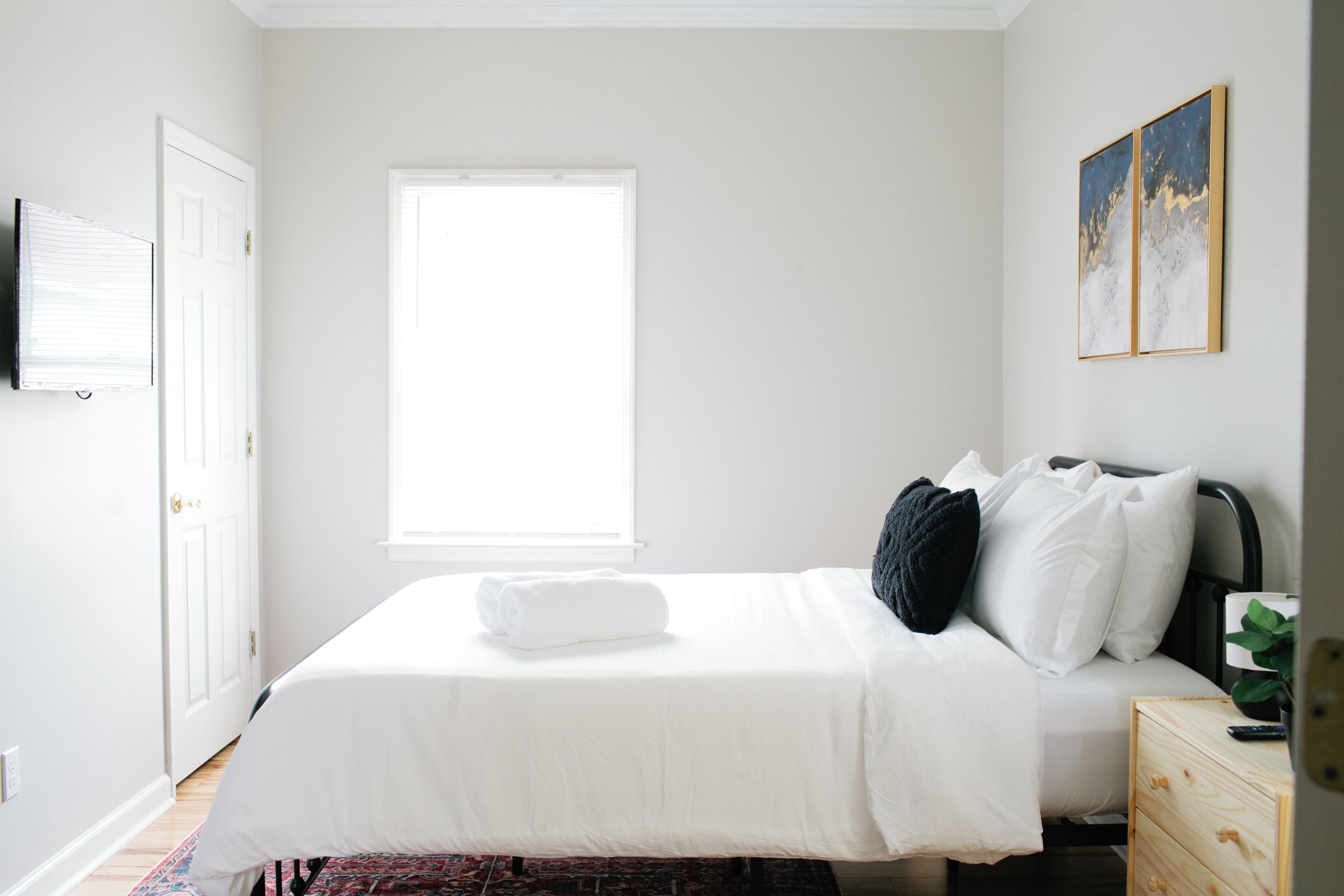 Une chambre à coucher avec un lit, une fenêtre, un tableau et une table de chevet.
