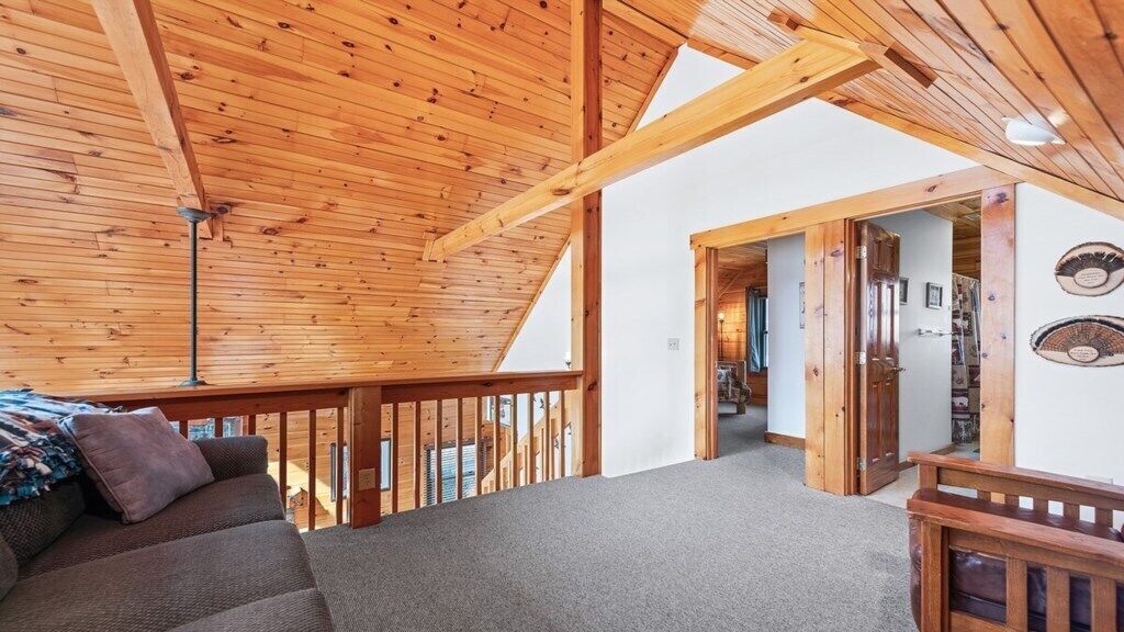 A wooden interior with a sofa, a ceiling fan, and a door leading to another room.