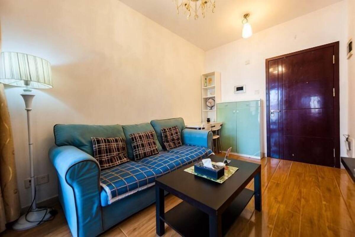 A living room with a sofa, a coffee table, a lamp, and a wooden floor.