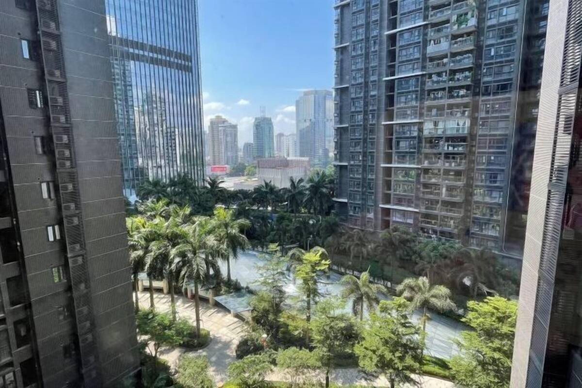 A high-rise building with multiple floors, a courtyard with palm trees, and a view of other high-rise buildings in the background.