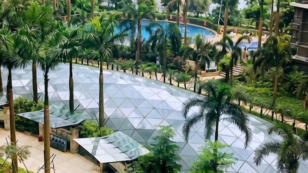 A resort with a swimming pool, palm trees, and a covered outdoor area. - Grace Apartment (Shenzhen)