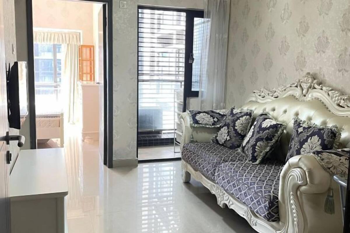 A room with a sofa, a door, and a view through a window.