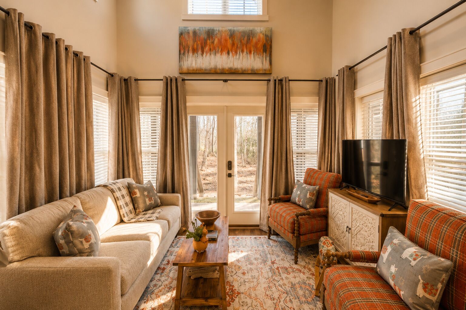 A cozy living room with a sofa, armchair, and a television on a wooden stand.