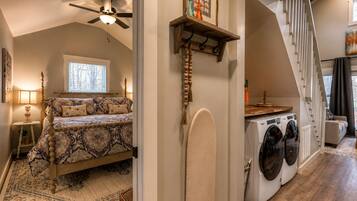 A bedroom with a bed, a ceiling fan, a window, and a nightstand.