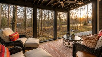 A spacious room with large windows, wicker furniture, and a ceiling fan.