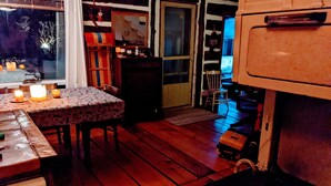 Una habitación acogedora con piso de madera, una mesa con mantel estampado y una chimenea con un leño dentro.
