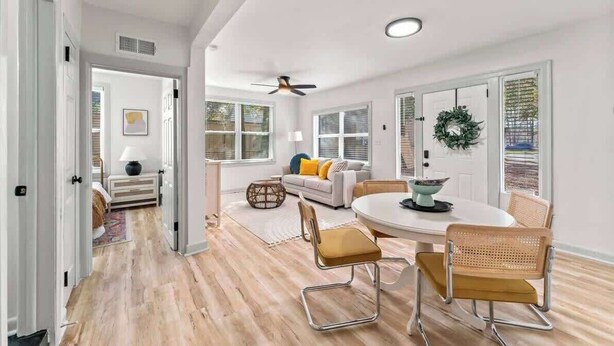 Un intérieur moderne comprenant un coin repas, un canapé et un ventilateur de plafond.