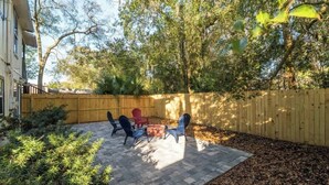 Une terrasse avec des meubles d’extérieur, un foyer en briques et une clôture en bois.