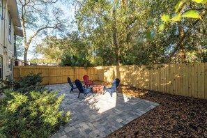 Une terrasse avec des meubles d’extérieur, un foyer en briques et une clôture en bois.