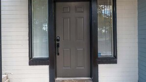 Une porte d’entrée avec un cadre noir, une serrure et un petit marchepied menant à la porte.