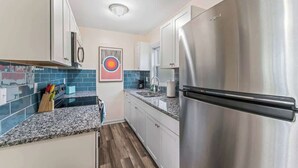 Eine moderne Küche mit Edelstahlgeräten, einer Granitabdeckung und einer blauen Fliesenrückwand.