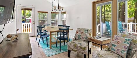 Una habitación soleada con una mesa de comedor, sillas, un sofá y un televisor.