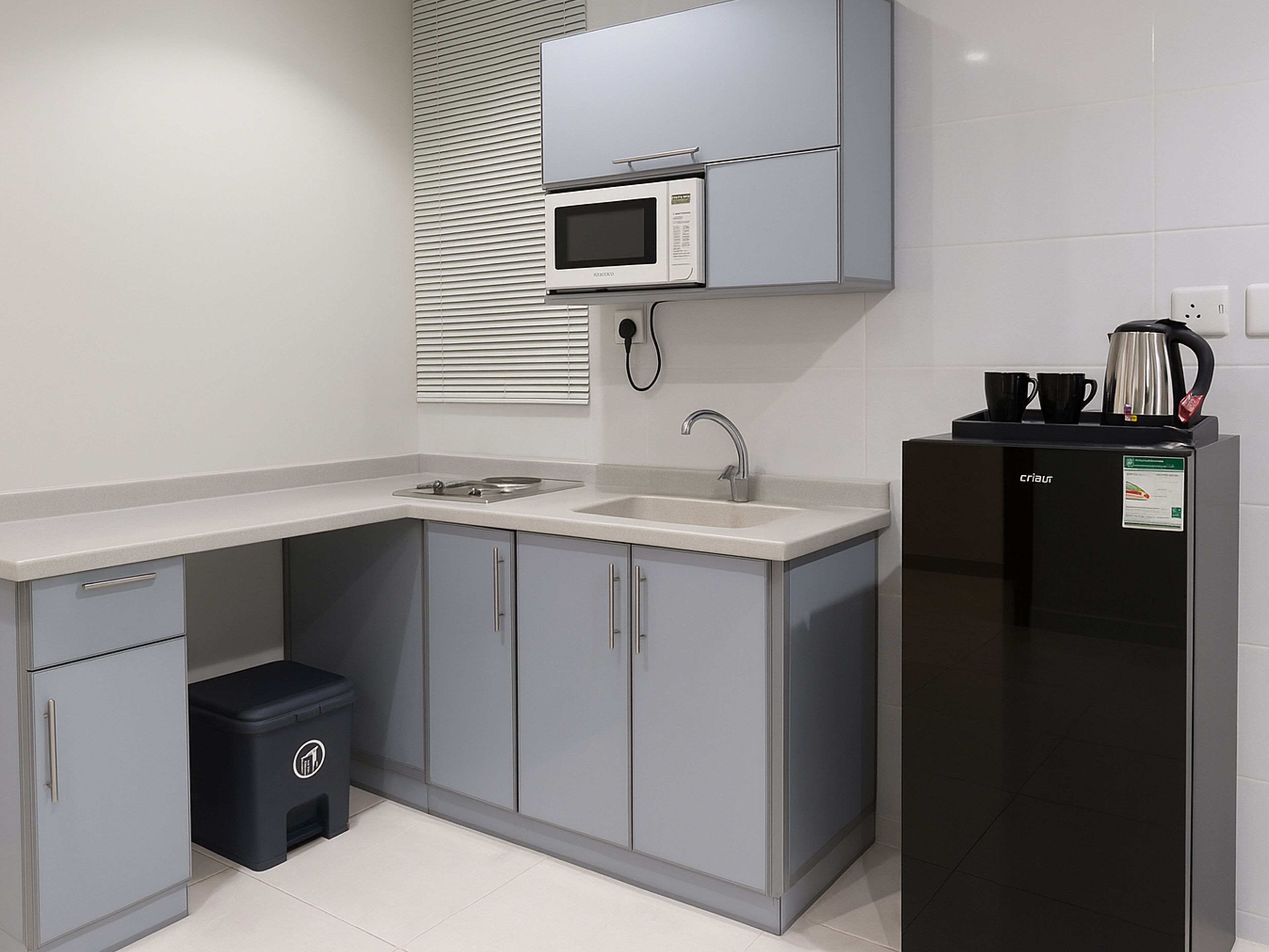 Una cocina moderna con armarios grises, un microondas integrado, un fregadero y un refrigerador negro.